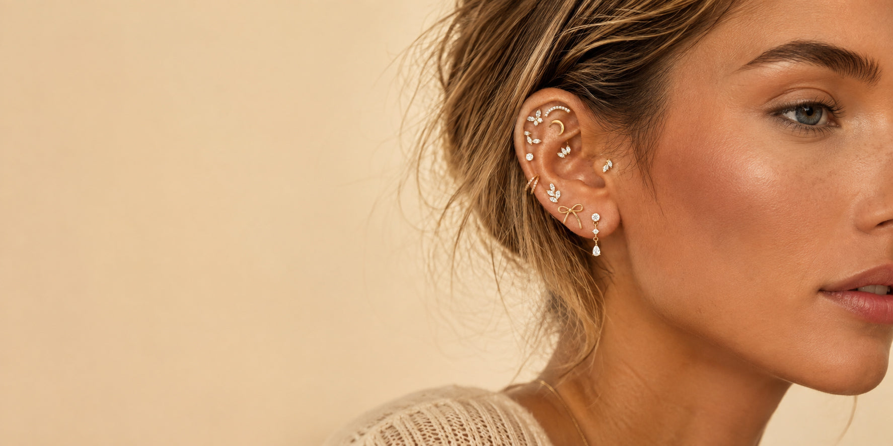 Kvinde med et kurateret ear stack af piercingsmykker med sløjfer og krystaller