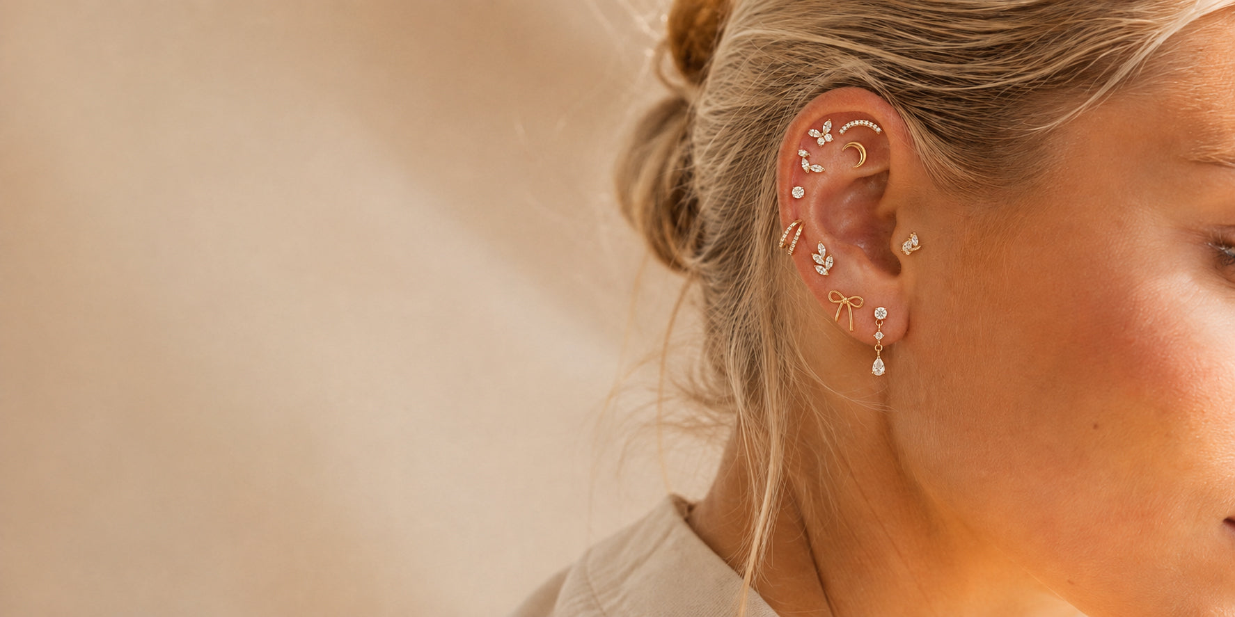 Kvinde med guldfarvede piercingsmykker i helix, conch og øreflip
